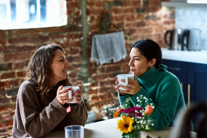 Two women enjoying hot drink having conversation