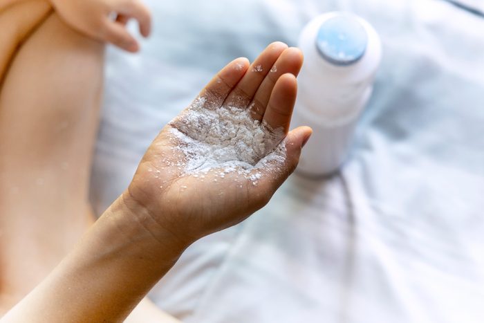 Close-up picture of mother's hand with baby powder, dangerous for health and breath system.