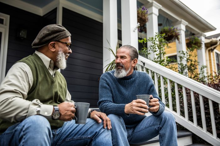 Senior men having coffee in front of suburban home