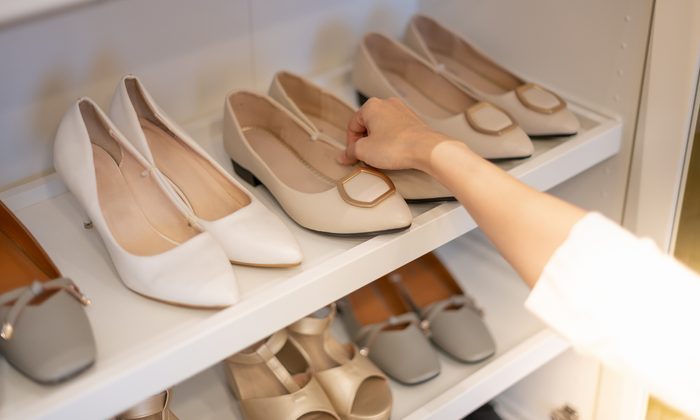 The woman holding shoes in her hands for choose and shopping looking at the shelves with numerous footwear.