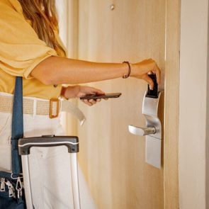 Businesswoman opening her hotel room door with a keycard after checking in