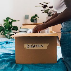 Woman packing donation box on bed at home