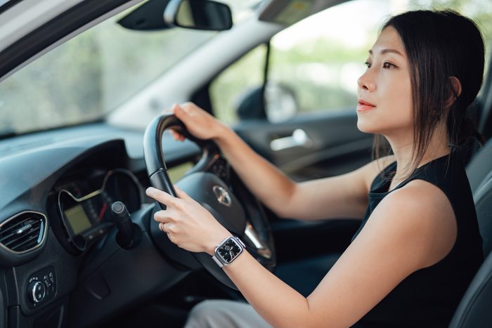 Side view of young Asian woman driving a car