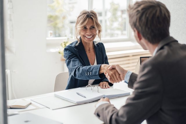 Happy businesswoman doing handshake with man at office