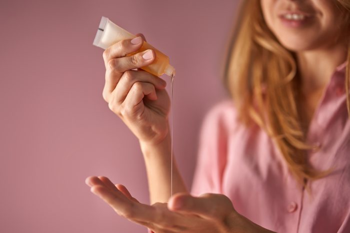 A girl in pink pours a gel-texture cosmetic onto her hand.