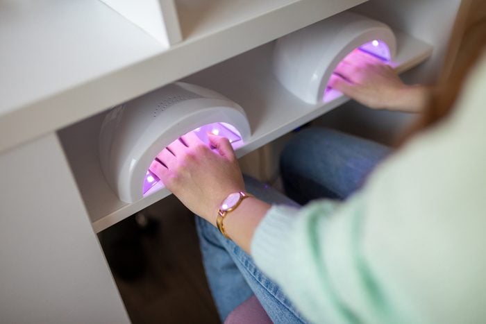 Young woman drying her nails with a UV lamp in a nail salon