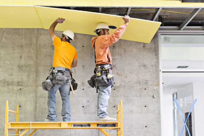 Construction workers applying insulation