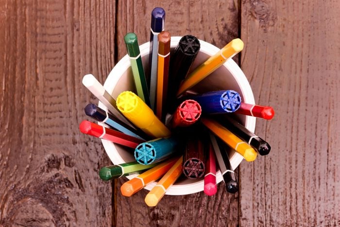 Still life, business, education concept. Crayons and markers in a Cup on a wooden table. Top view, copy space background.