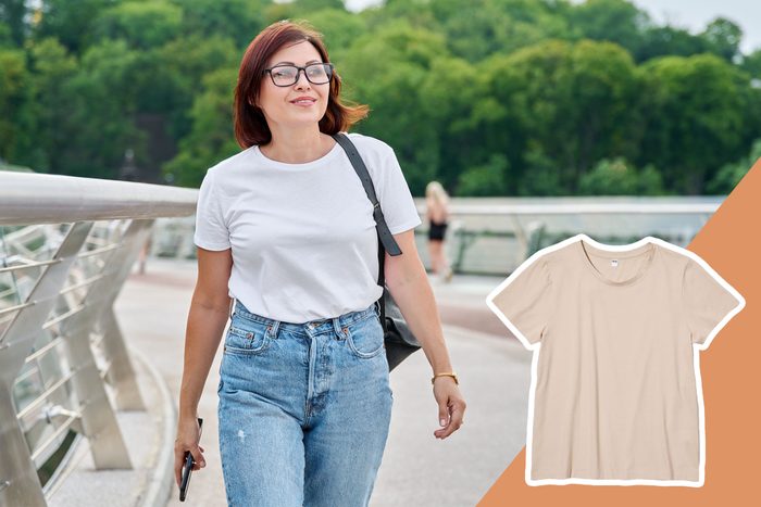 woman in a white t-shirt and jeans walking down the street
