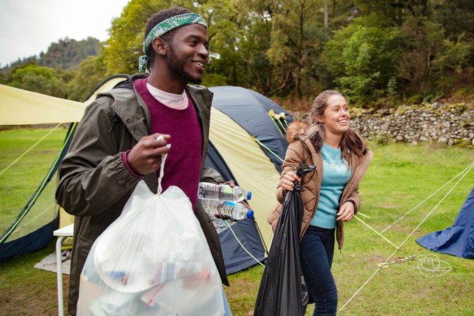 a couple walking with trash bags at a campground