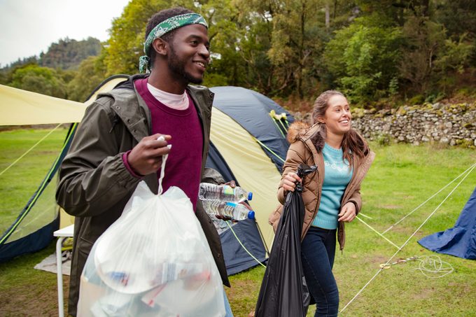 пара гуляет с мешками для мусора в палаточном лагере