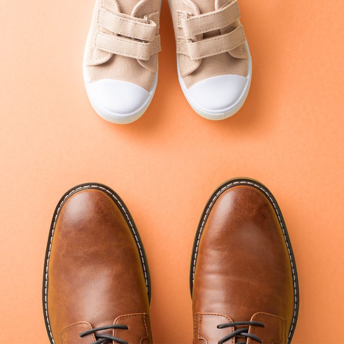 large dad shoes with small kid shoes on orange background
