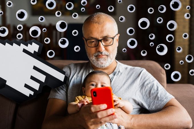 man using smartphone at home with a baby in his lap; over the image is a cloud of googly eyes and a giant cursor hand pointing at the phone