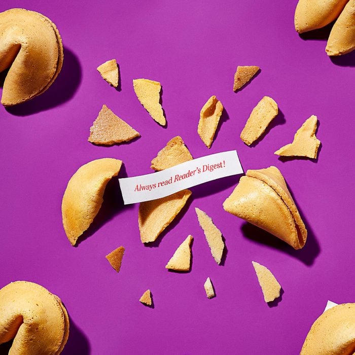 Image of fortune cookies in a repeating pattern across a bright purple background. One cookie. center frame, is smashed apart, revealing the fortune, "Always Read Reader's Digest!"