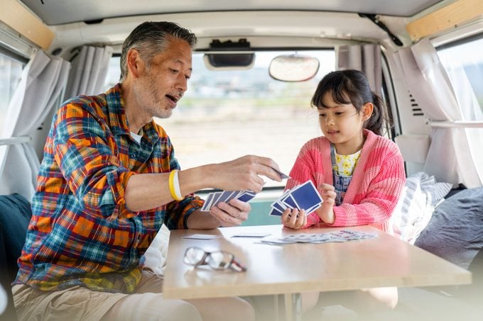 father and daughter playing cards in a van