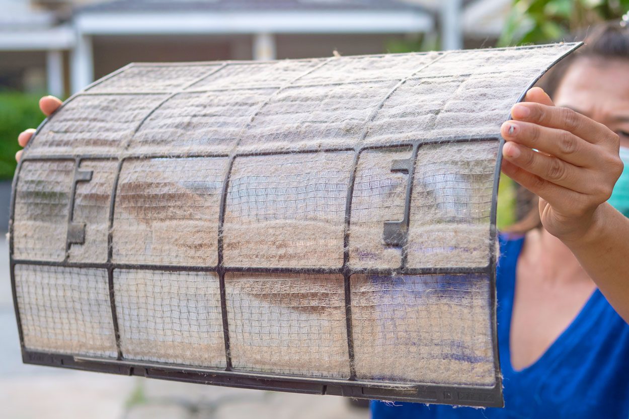A Woman Holding A Dirty And Dusty Air Conditioner Filter to clean the filter