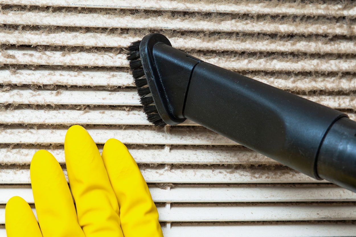 Hand In Yellow Glove And Vacuum Cleaner Pipe cleaning ventilation vents for home air conditioning