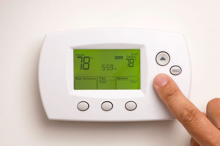 Male Hand On Digital Thermostat Set At 78 Degrees