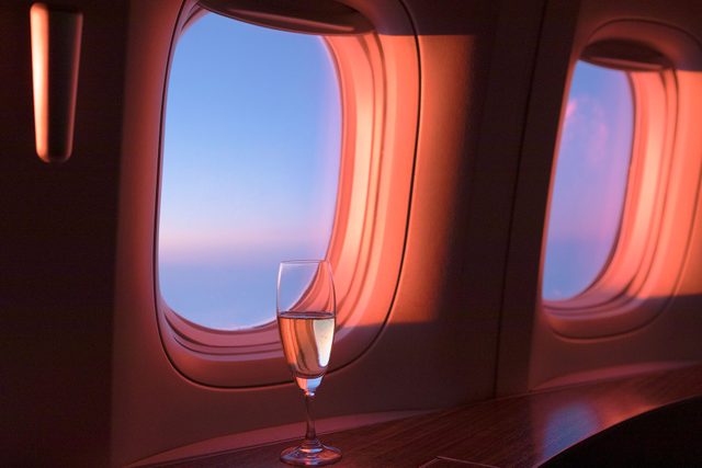 Glass Of Champagne In First Class during sunset in the airplane windows