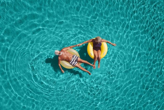 High angle view photo of a senior couple floating in the ocean while using swimming and floating devices
