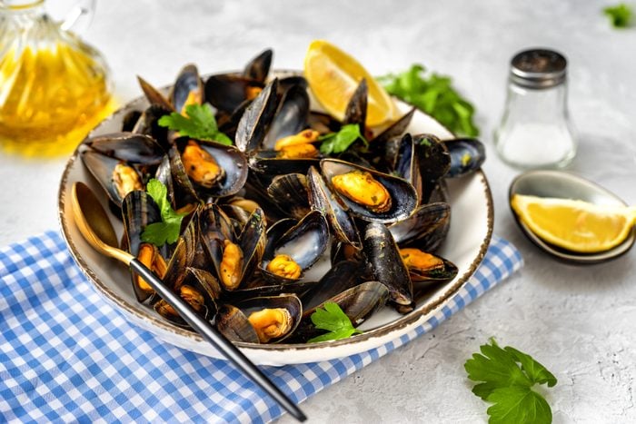 Close up of plate with cooked mussels with parsley and lemon