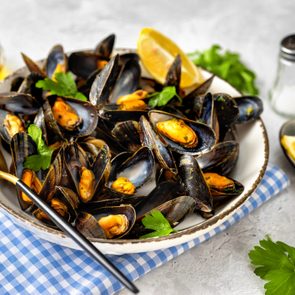 Close up of plate with cooked mussels with parsley and lemon