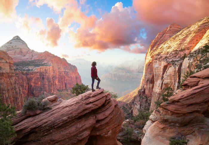 Adventurous Woman at the edge of a cliff is looking at a beautiful landscape view in the Canyon