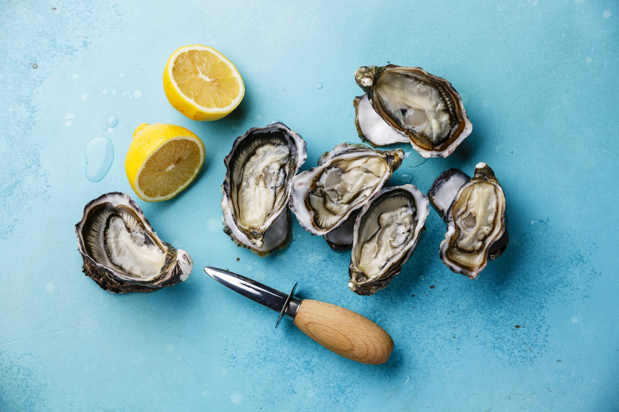 Open Oysters and lemon on blue background