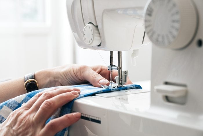Hands using a sewing machine to tailor clothes