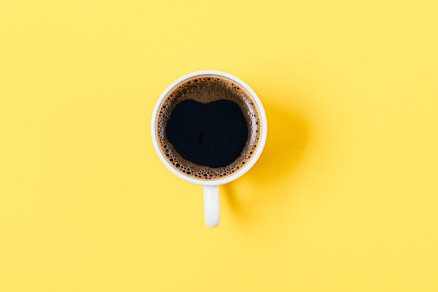 One coffee cup in center of bright yellow background