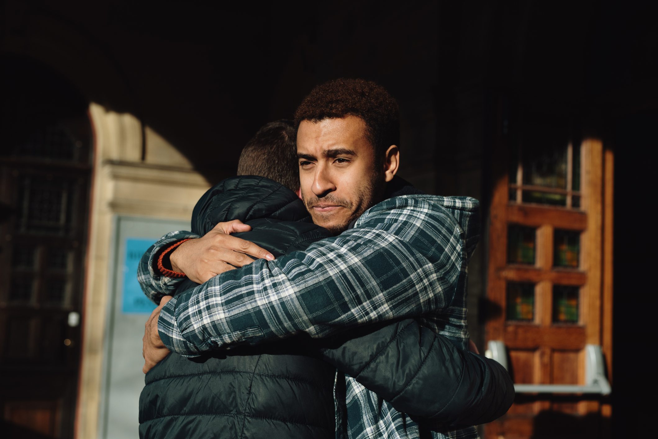Two men hug outside of a building