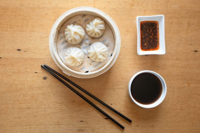Steamed soup dumplings with side dishes of sauces and chop sticks