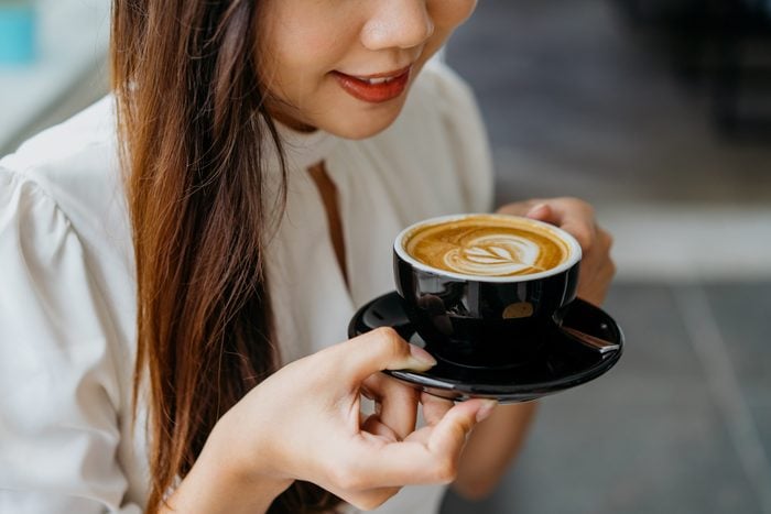 Young asian woman holding a cup of coffee with saucer