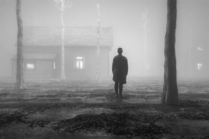 Spooky man standing in the fog outside of a haunted house
