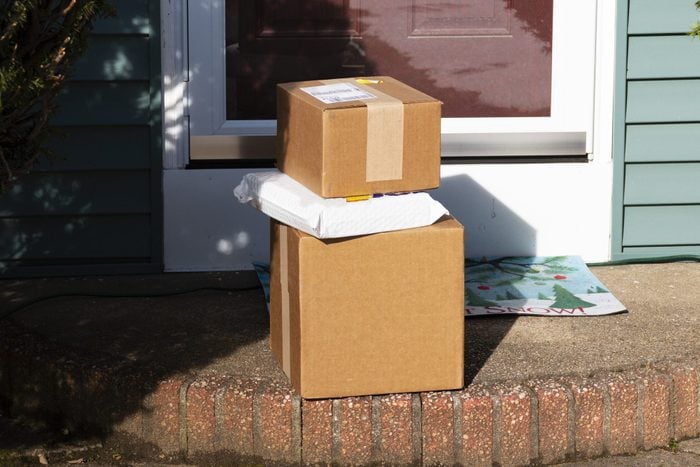 Three packages stacked on top of each other exposed on front stoop