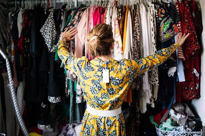 Fashionable woman in yellow dress choosing from clothes rack