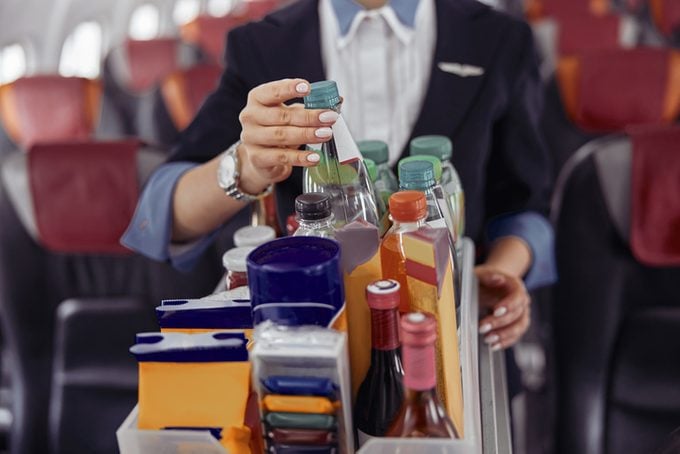Stewardess take water bottle from trolley cart
