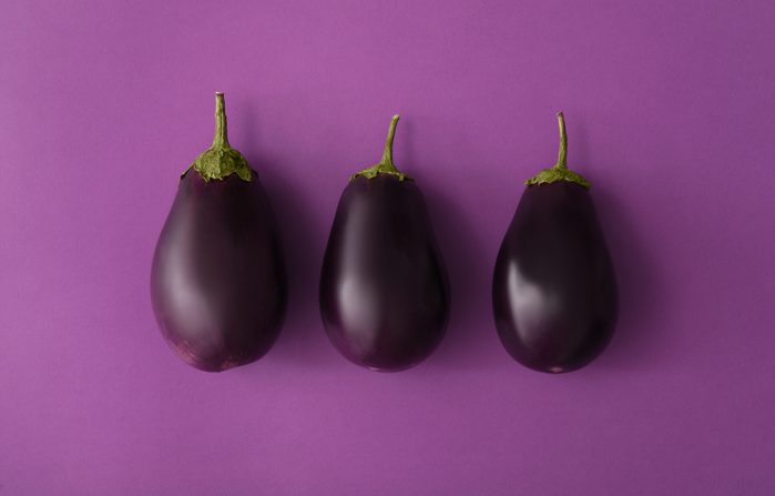 Raw ripe eggplants on purple background