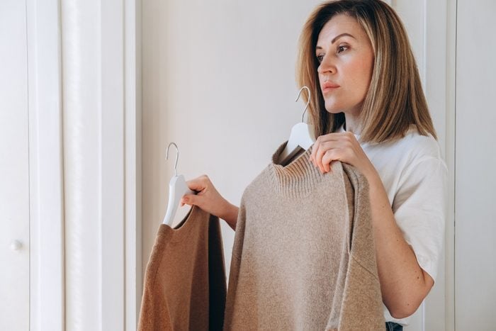 woman choosing a cashmere sweater near the mirror in her home dressing room