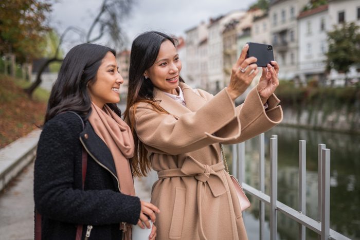 Smiling Female Friends Taking Selfie With Smart Phone