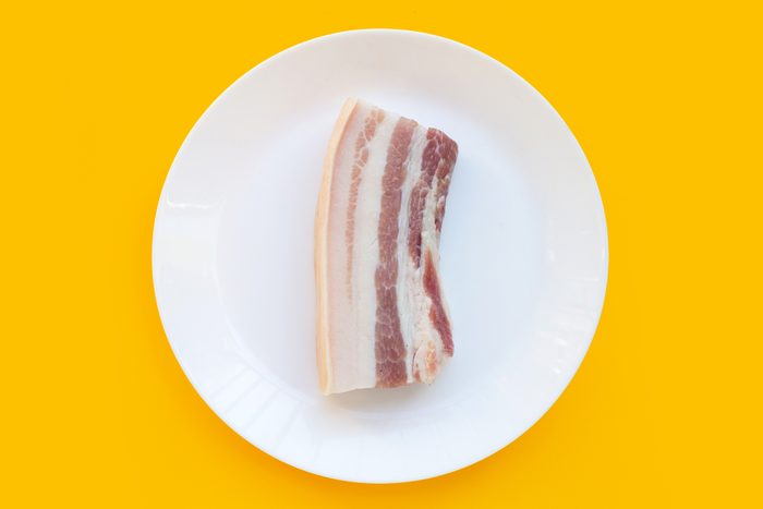 Streaky pork in white plate on yellow background.