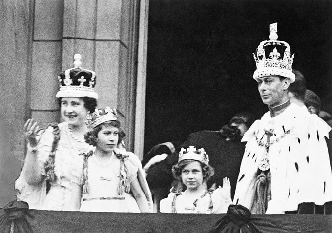 The crowned King George VI and Queen Elizabeth with Princess Elizabeth and Princess Margaret Rose, acknowledging the cheers of the crowd from the balcony of Buckingham Palace on their return from Westminster Abbey
