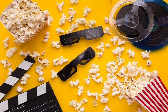 Clapperboard, 3D glasses and popcorn on yellow background