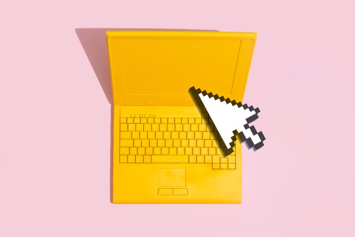 yellow laptop on a pink background with a digital computer mouse cursor on top