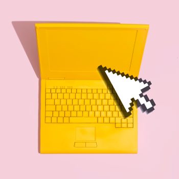 yellow laptop on a pink background with a digital computer mouse cursor on top