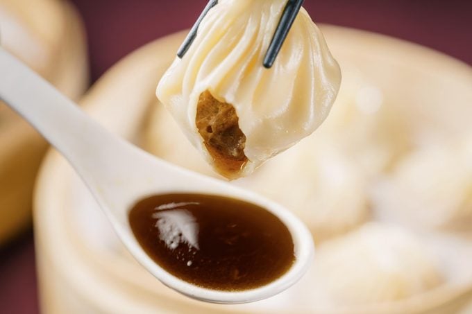 dipping Soup Dumpling into a spoon of sauce