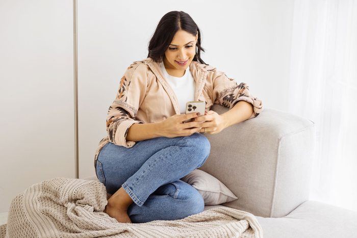 Young Woman Sitting On A Couch Using A Cellphone