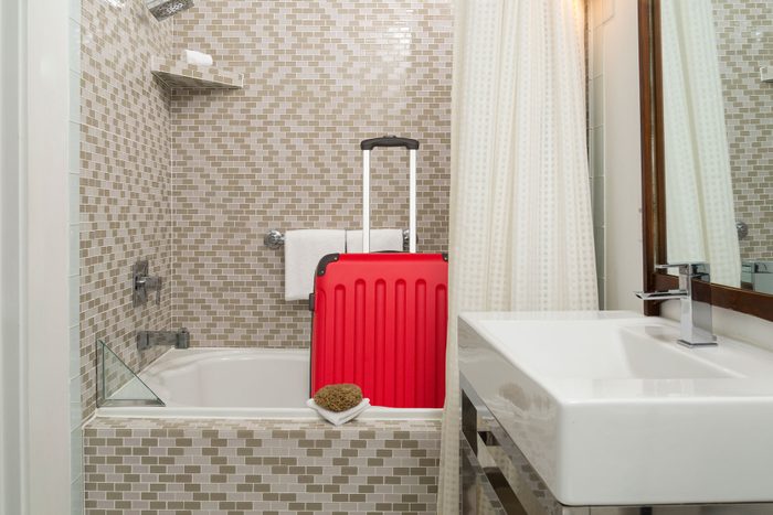 red suitcase in the bathtub of a hotel bathroom