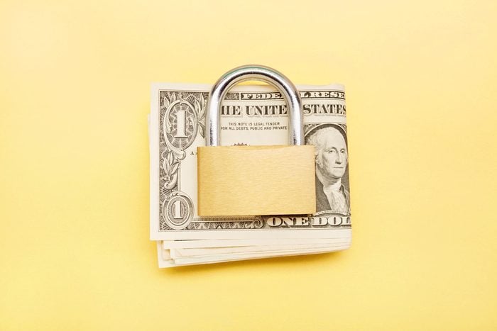 money with a pad lock on top, yellow background