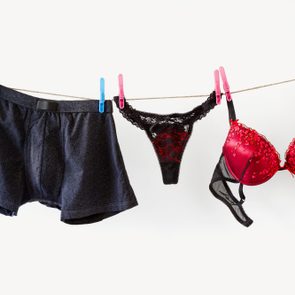 mens and womens underwear hanging on a laundry clothesline. boxers, panties, and bra.